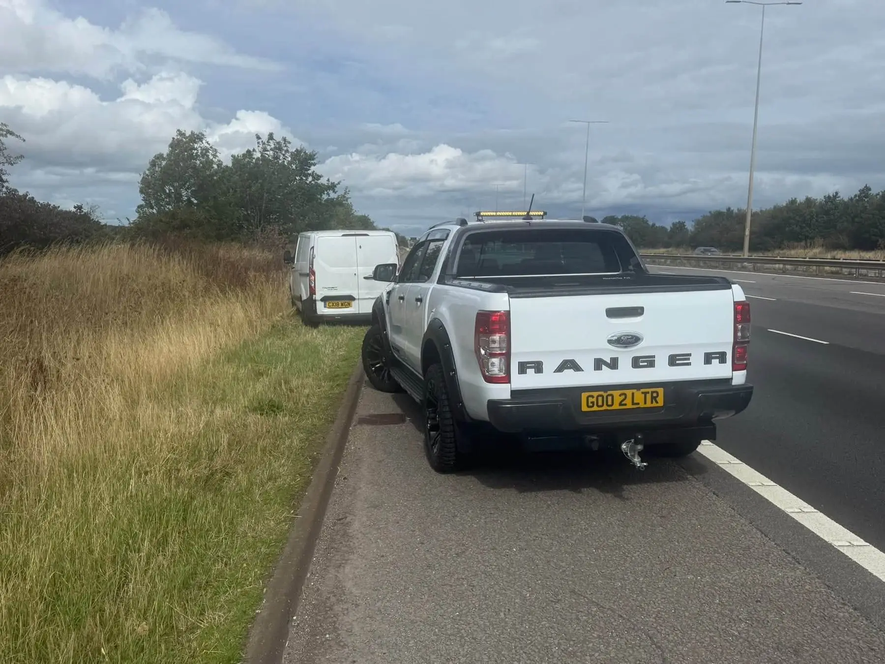 LTR Ford Ranger parked on the hard shoulder behind a van with a blown tyre