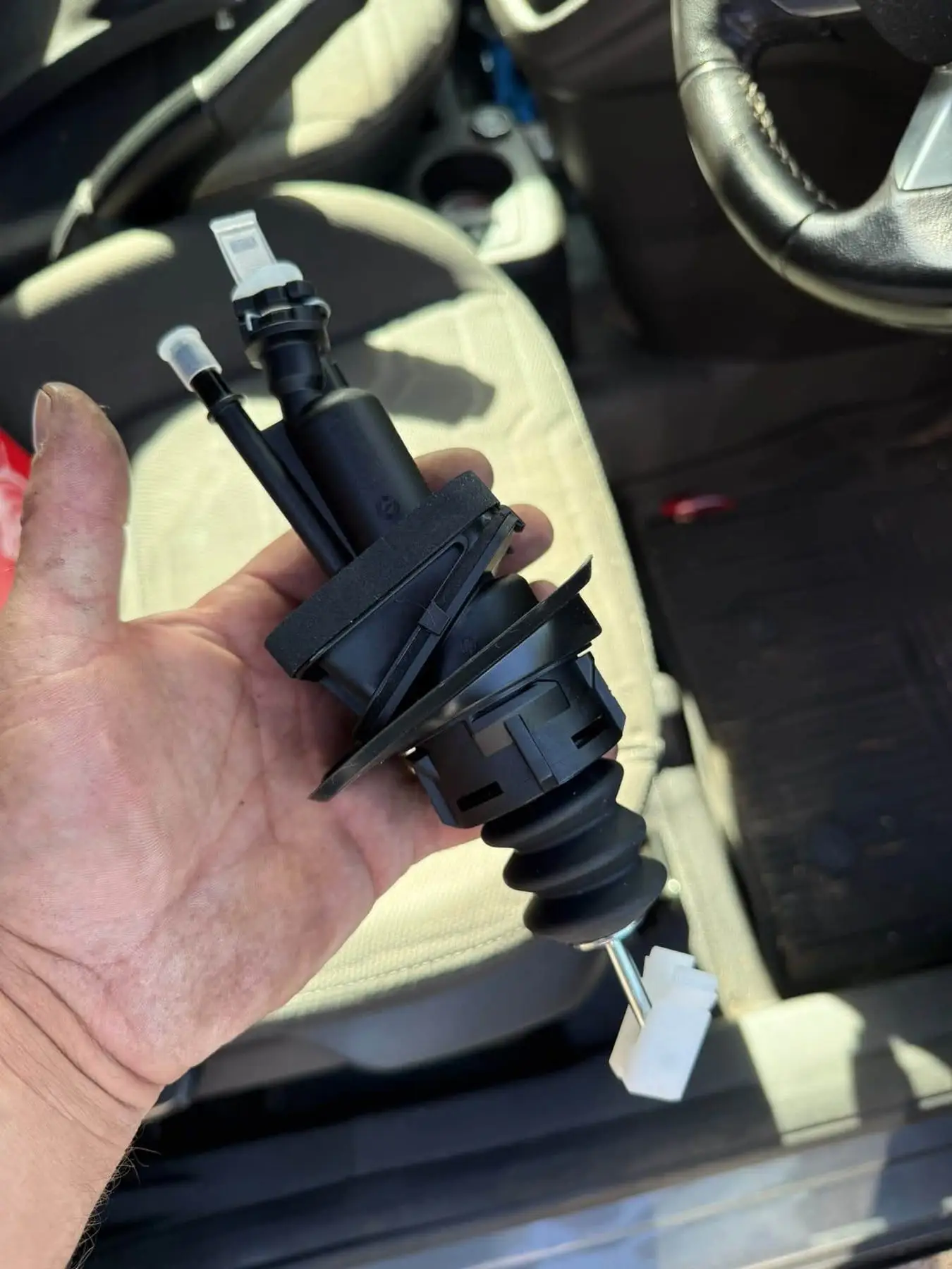 Replacement clutch slave cylinder held in a gloved hand before fitting
