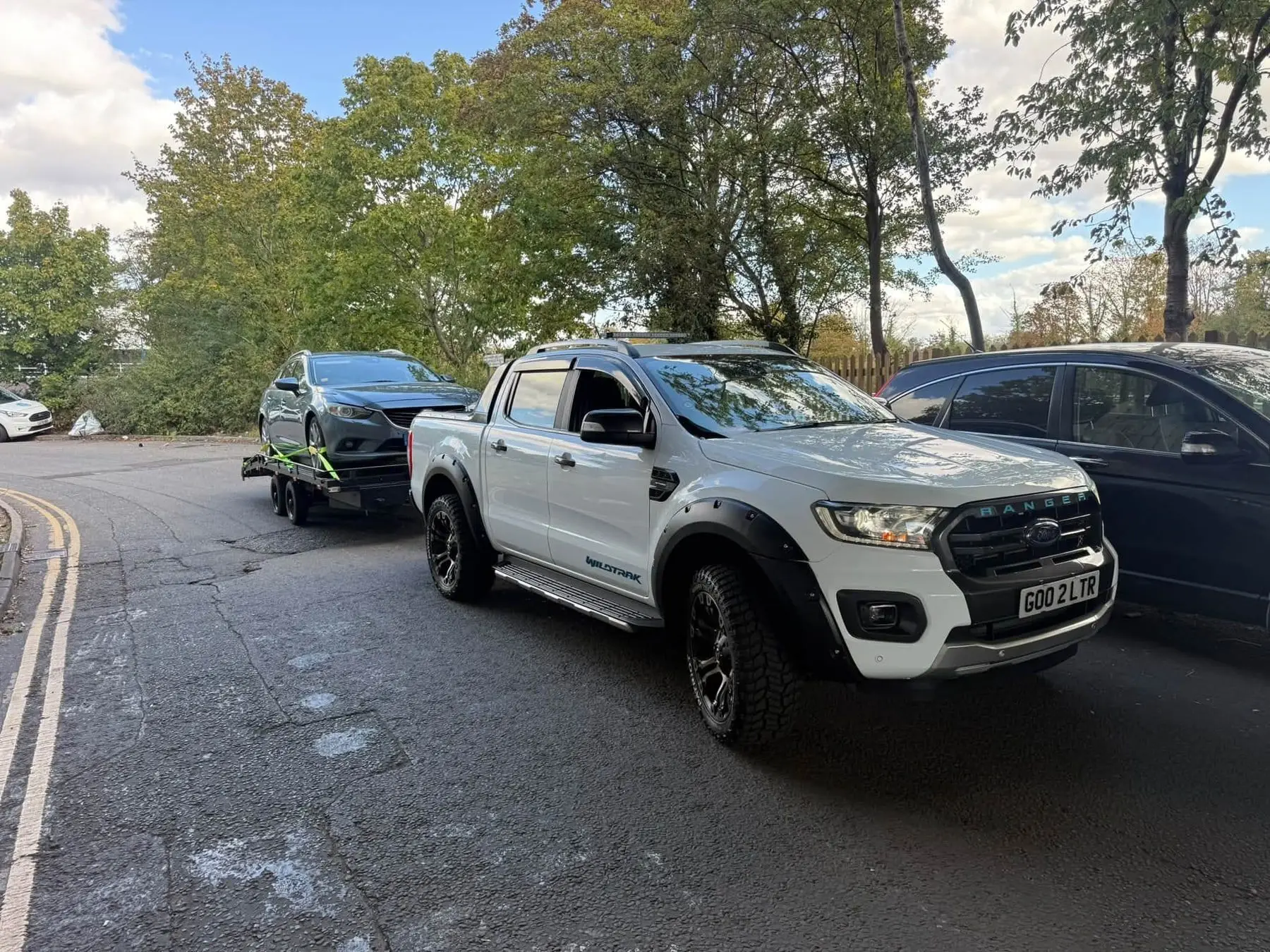 The white LTR Ford Ranger Wildtrak with the transporter trailer and a loaded car behind it